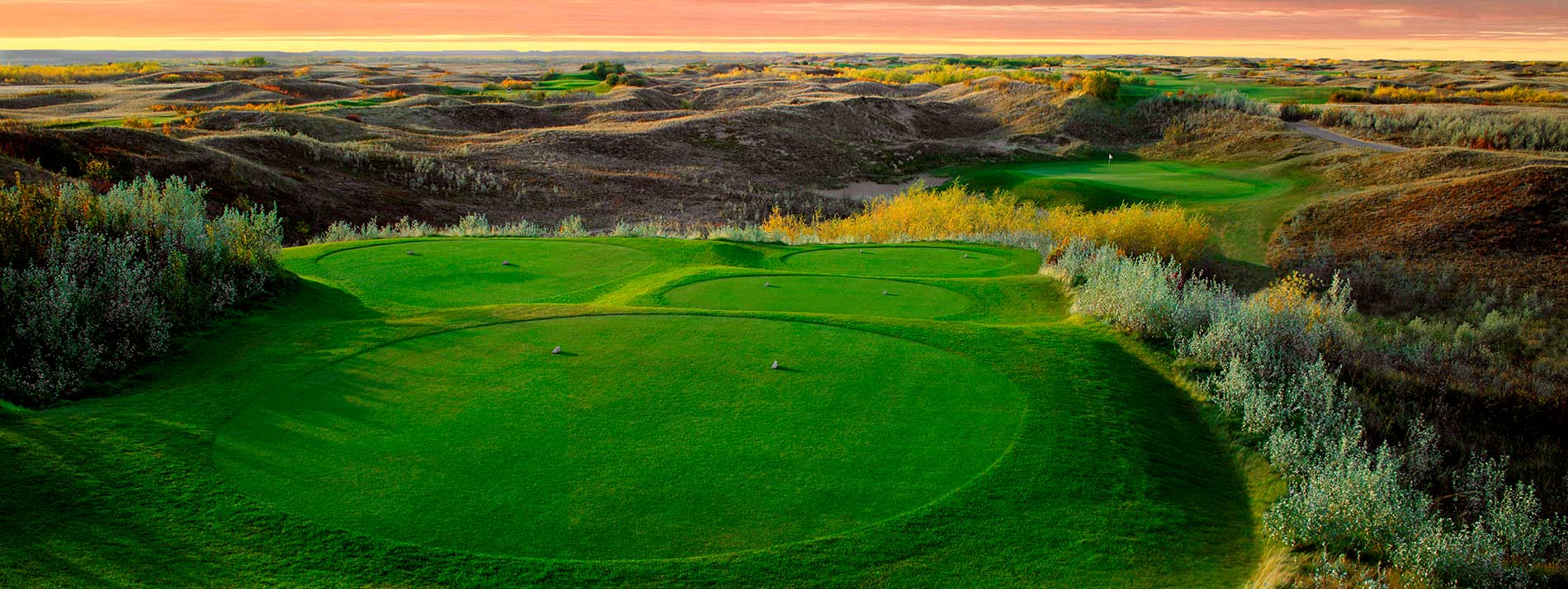 golf course surrounded with rolling hills of northern prairies at sunset